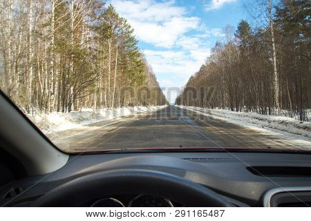 View Of The Road Through The Windshield. Snow On The Sidelines. Wet Asphalt Road. Blue Sky With Clou
