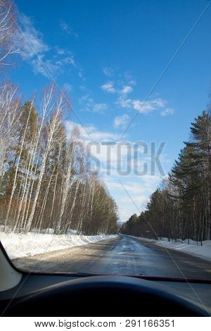 View Of The Road Through The Windshield. Snow On The Sidelines. Wet Asphalt Road. Blue Sky With Clou