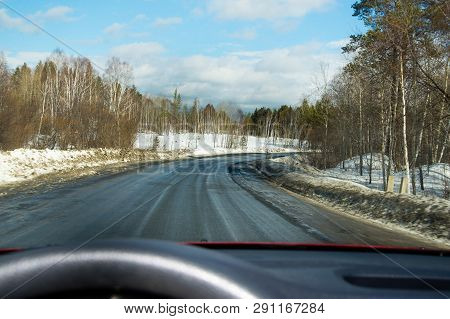 View Of The Road Through The Windshield. Snow On The Sidelines. Wet Asphalt Road. Blue Sky With Clou