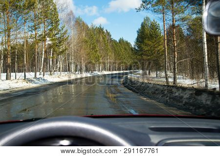 View Of The Road Through The Windshield. Snow On The Sidelines. Wet Asphalt Road. Blue Sky With Clou