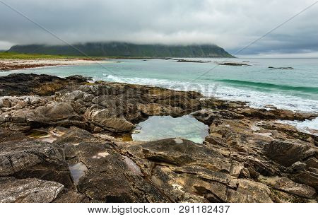 Summer Cloudy View Of The Beach With Pool In Middle Of Stones ( Ramberg, Norway, Lofoten).