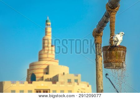 Pigeon Drinks Water At Old Well Fountain, Iconic Landmark In The Middle Of Souq Waqif In Doha City C