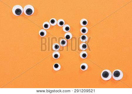 Googly Eyes. Two Strange Persons With Mad Eyes Look At Some Crazy Toy Eyes On Orange Background In T