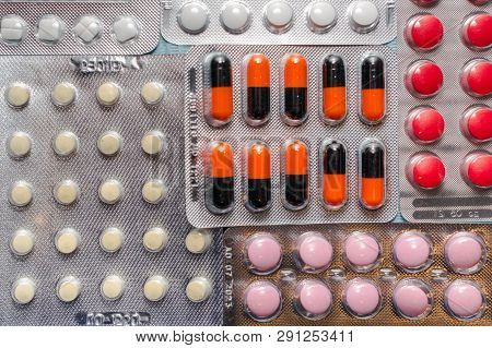 Multicolored Tablets And Capsules In Blisters Close-up, Top View. The Concept Of Treating Human Dise