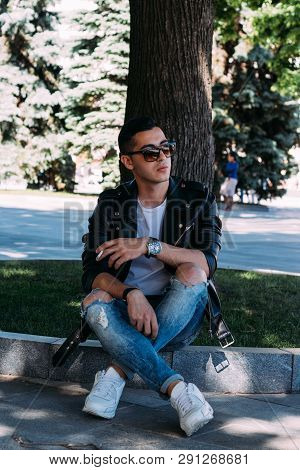 A Young Guy Smokes Around A Tree In The City.bad Habit.smoking In A Public Place