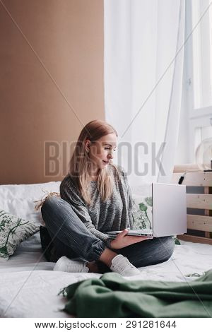 Young Woman Working On Computer In Bed. Relaxing At Home.