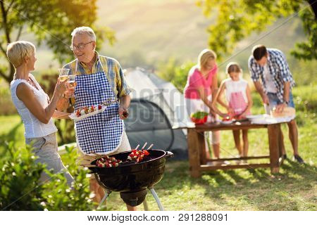 grandparents drinking  wine and making barbeque for family
