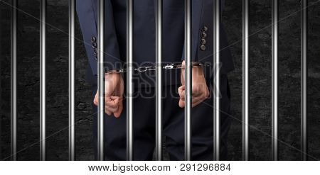 Close convicted man with handcuffs behind grids