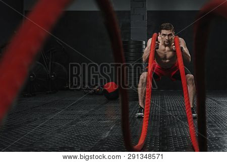 Young Strong Man Doing Battle Ropes Exercise At The Gym. Athlete Working Out With Battle Rope. The S