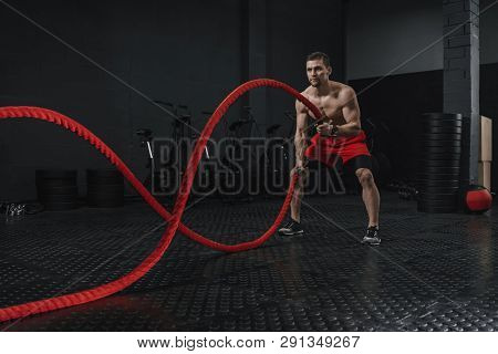 Young Athlete Doing Battle Ropes Exercise At The Gym. The Sport Motivation Concept. Copy Space.