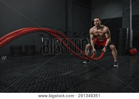 Man Wear Red Shorts Doing Battle Ropes Exercise At The Gym. The Motivation Sport Concept. Copy Space