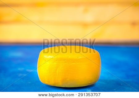 Goat Cheese Wheel On Blue And Yellow Background