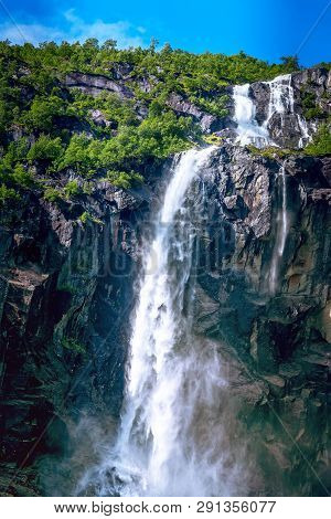 Waterfall And Green Trees On The Way To Briksdal Or Briksdalsbreen Glacier In Olden, Norway