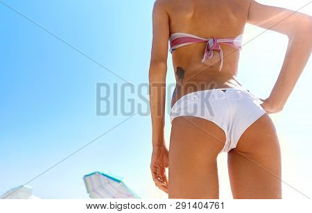 Beautiful Sexy Young Woman Walks On The Beach. Woman Buttocks Slim Figure On The Beach With Sky Back