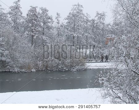 Two People Walking Through Snow-covered Winter Landscape In The Dutch Town Of Vlaardingen.