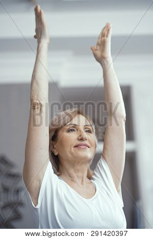 A Woman Over 50 Years Old Loves Yoga. She Raised Her Hands In The Pose Of Asana. She Likes Yoga At H