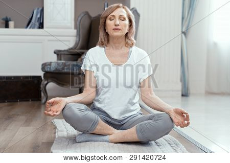 A Woman Takes Yoga At Home. Woman Over 50 Years Old. She Took The Pose Of The Asana On The Floor. Cl