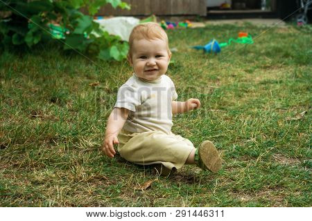 Little Toddler Boy Trains His Skills In Crawling And Sitting. The Child Happily Crawls And Sits On T