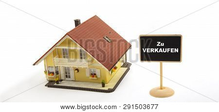 Zu Verkaufen Means For Sale. Concept Business Real Estate With Toy House And Little Blackboard Sign 