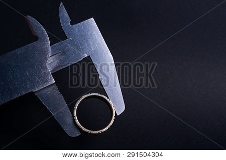 Vintage Steel Caliper Measuring Diameter Of Sterling Silver Male Ring Closeup. Ring In Focus. Tool I