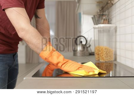 Young Man Cleaning Oven Cooktop With Rag In Kitchen, Closeup