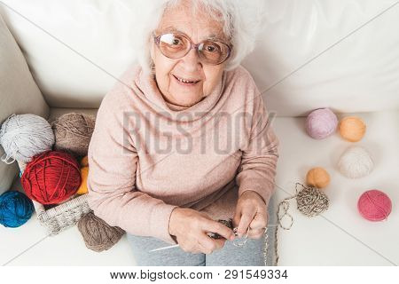 Smiling eldery woman knitting with colorful laces balls