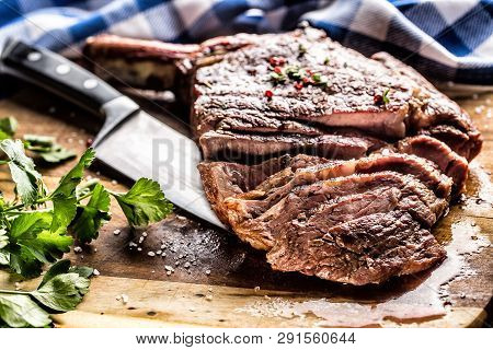 Freshly Grilled Tomahawk Steak On Slate Plate With Salt Pepper Rosemary And Parsley Herbs. Sliced Pi
