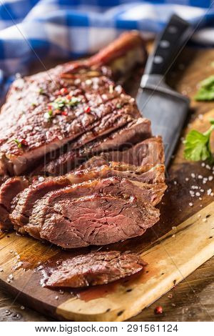 Freshly Grilled Tomahawk Steak On Slate Plate With Salt Pepper Rosemary And Parsley Herbs. Sliced Pi