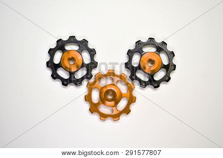 Color Rollers, Black, Golden Gears For Bicycle Rear Derailleur On A White Background In Middle, With