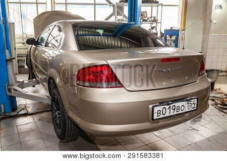 Novosibirsk, Russia - 08.01.2018: Beige Used Car Chrysler Sebring With An Open Hood Raised On A Lift