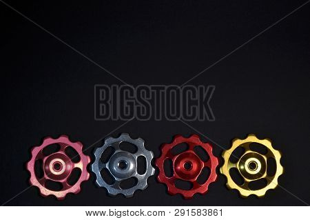 Color Rollers, Pink, Silver, Red, Golden Gears For Bicycle Rear Derailleur On Black Background In Bo
