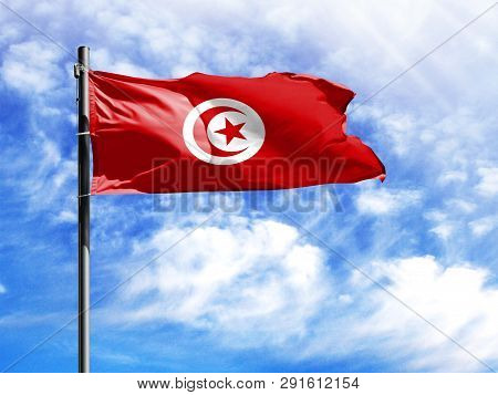 National Flag Of Tunisia On A Flagpole In Front Of Blue Sky.