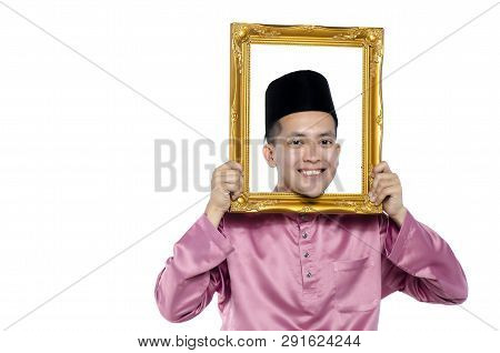 Portrait Of Young And Handsome Asian Man With Traditional Clothing Holding Blank Frame Over White Ba