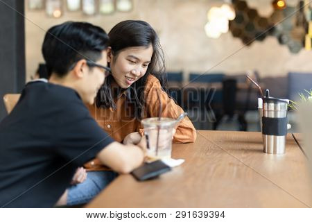 Happy Female Friend Looking At Cell Phone In Cafe.