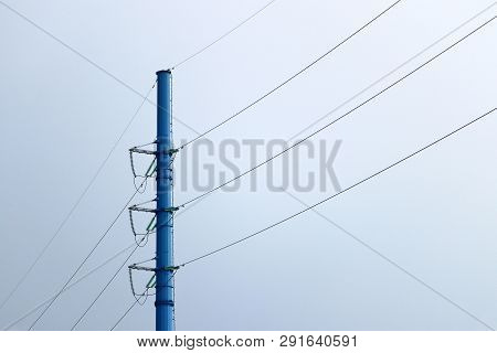 Power Line Post With Electrical Wires And Capacitors Isolated On Blue Sky Background. Electricity Tr