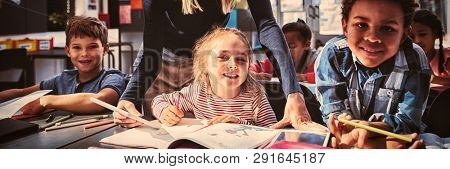 Teacher helping schoolkids with their homework in classroom at school
