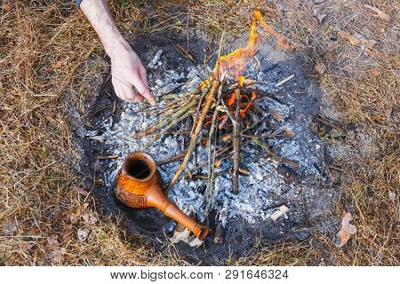 At The Stake In The Spring Forest, A Clay Turkish Coffee Pot Is Heated Against The Grass. In The Fra