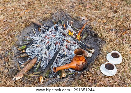 At The Stake In The Spring Forest, A Clay Turkish Coffee Pot Is Heated Against The Grass.