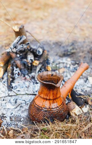 At The Stake In The Spring Forest, A Clay Turkish Coffee Pot Is Heated Against The Grass.