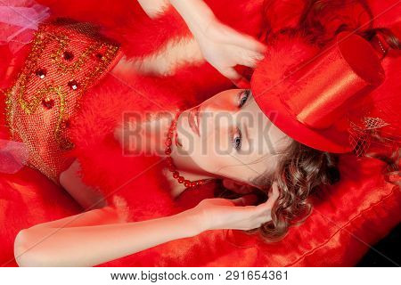 Sexy Burlesque Dancer Stripper Posing With Sweet Lollipop, In Red Corset And Red Hat With Curly Hair