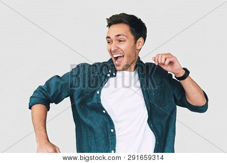 Cheerful, Funny Man Wearing Denim Shirt And White T-shirt, Jumping With Raised Arms, Celebrating Vic