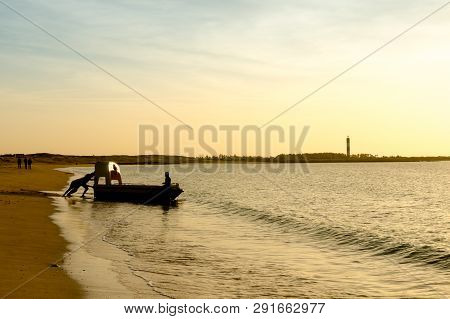 Silhouette Of Men Pulling A Boat Into The Sea At A Beach In Gujarat