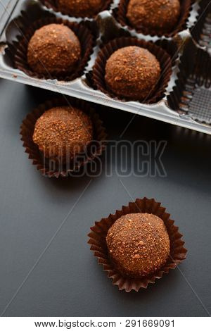 Chocolate Petit Fours Over Black Background. Top View.