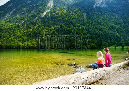 Two Cute Sisters Enjoying The View Of Deep Green Waters Of Konigssee, Known As Germany's Deepest And