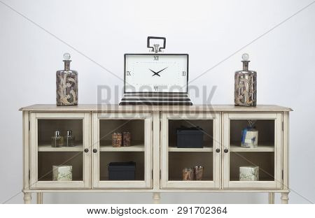 Glass Fronted Sideboard And Ornaments And A Large Clock On A White Background
