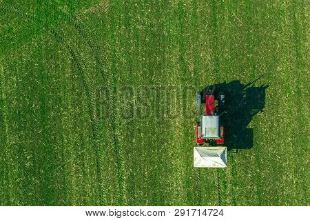 Agricultural Tractor Is Fertilizing Wheat Crop Field With Npk Fertilizers, Aerial View From Drone Po