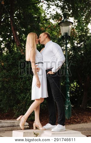 Beautiful Cuple Stand On The Stairs And Hug Each Other. Man And Woman Walking In The Park. Love Stor