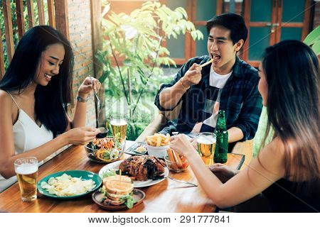Asian People Cheering Beer At Restaurant Happy Hour And Laughing.