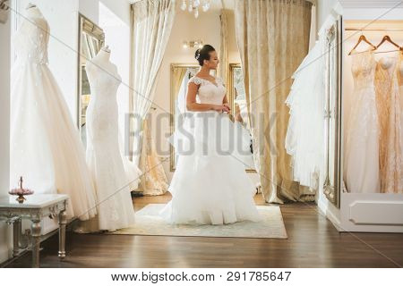 Beautifu bride choosing wedding dress in a wedding salon