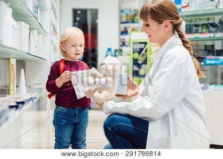 Pharmacist woman with child customer and her plush toy in pharmacy